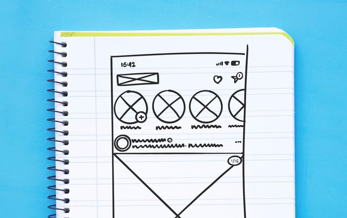 A sketch of a website design displayed on a notebook, showcasing layout and elements in a creative format.